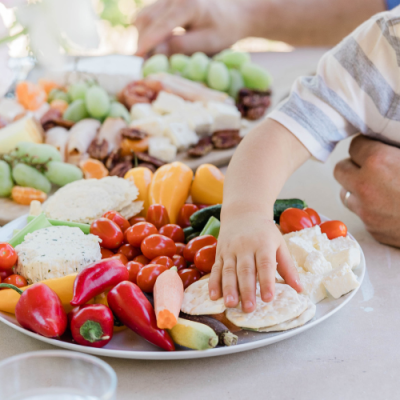 Mano de un niño cogiendo alimentos de un plato